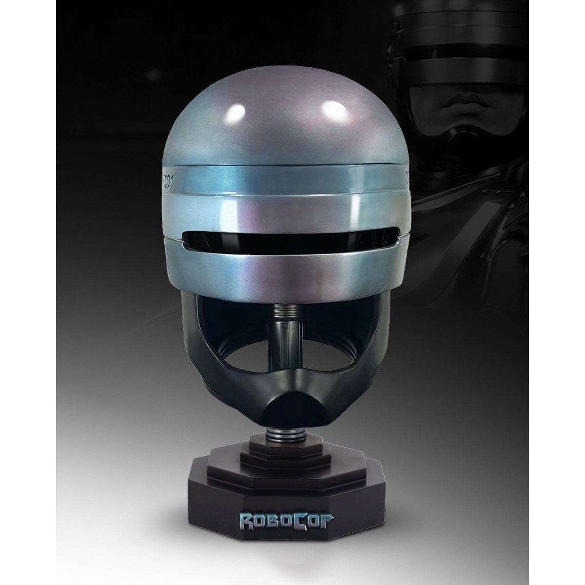 A RoboCop helmet display stand featuring a metallic silver and blue helmet replica on a black base with the 'RoboCop' logo, set against a dark background with a faint character silhouette.